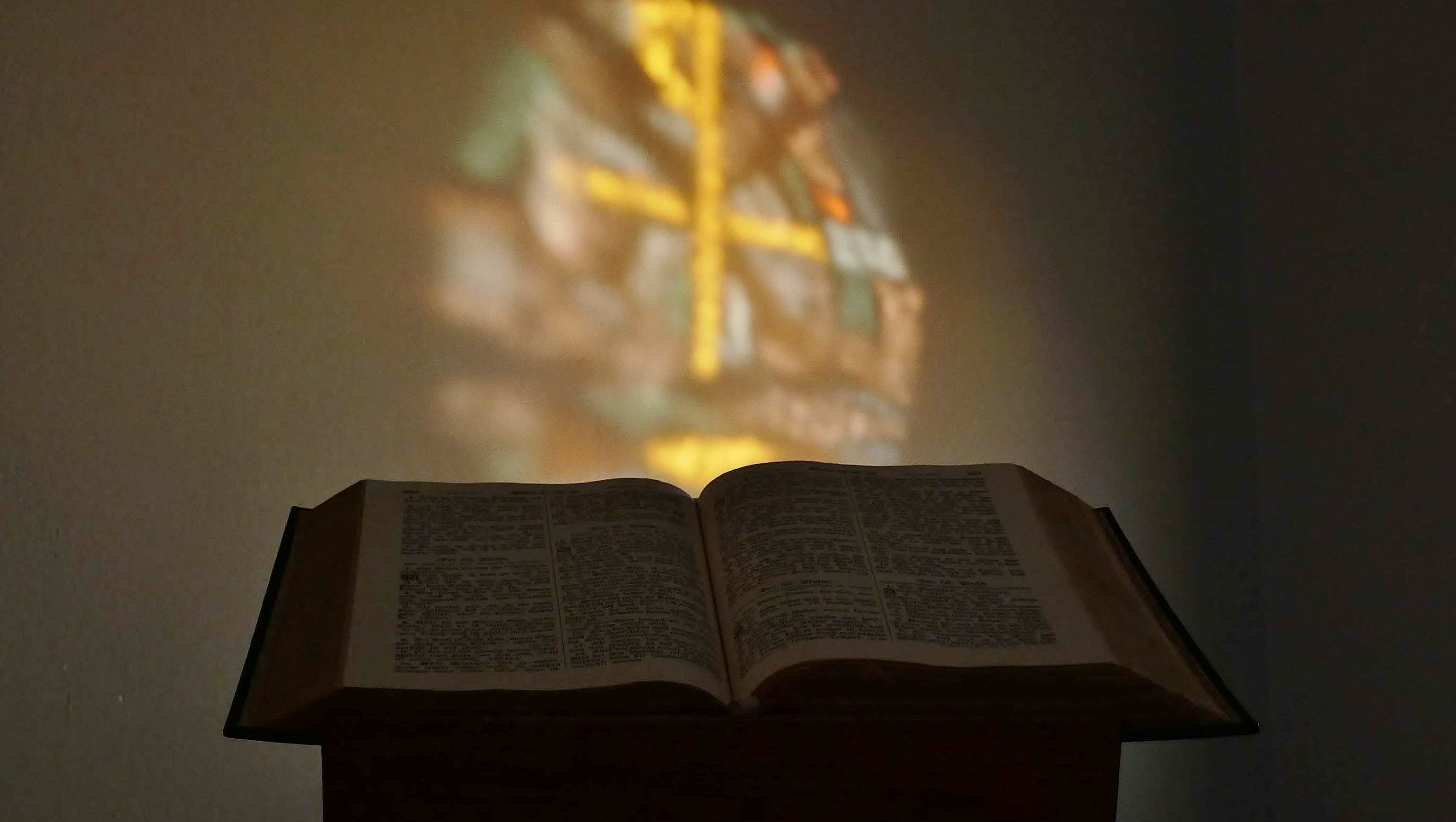 Altarbibel im MLH Bierde, hinter der sich das Tauffenster spiegelt