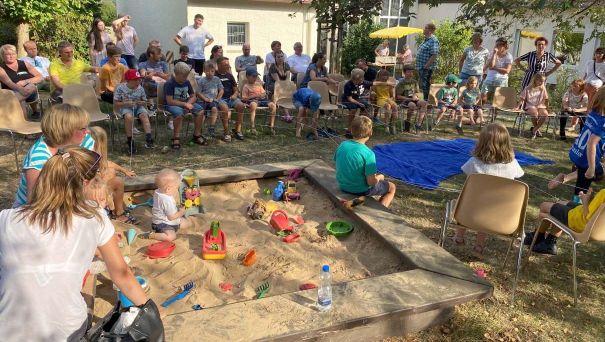 Familien mit Kindern, die im Sand spielen bei Kirche Kunterbunt