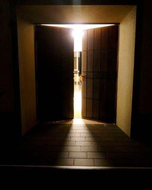 geöffnete Tür im Dunkel, aus der Licht durch den Türspalt scheint